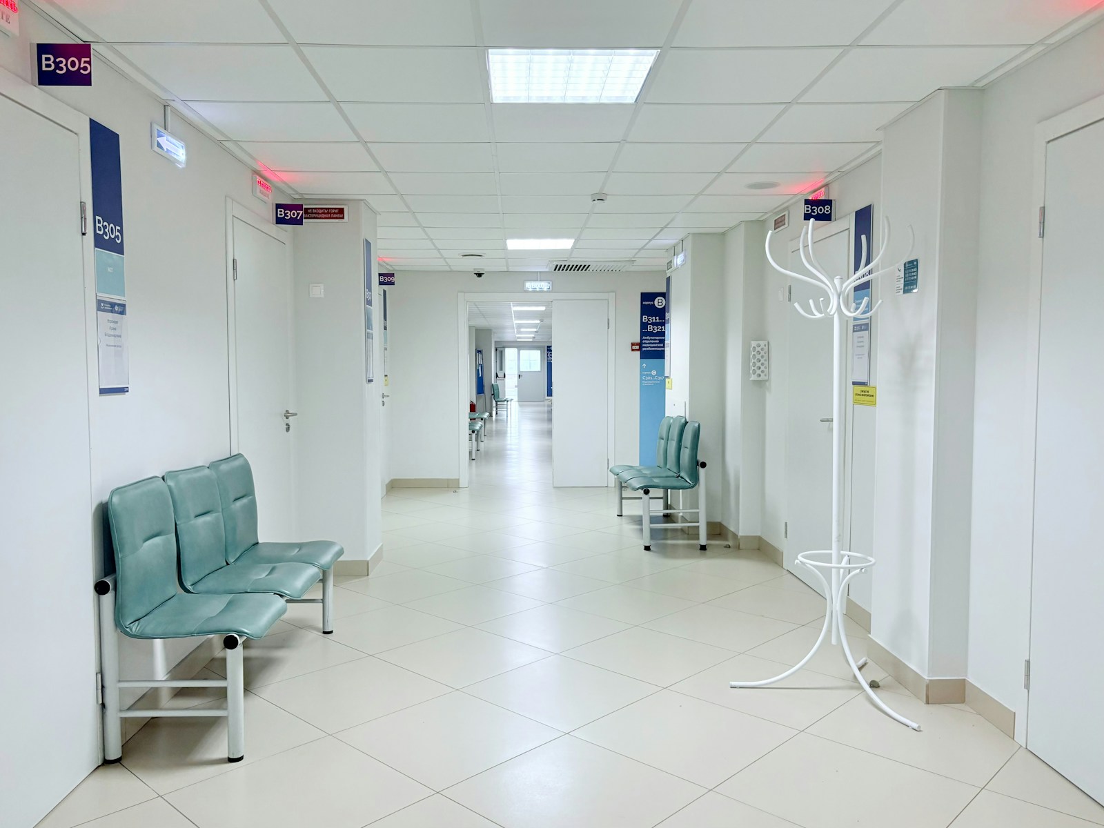 Corredor de clínica vazio, com bancos e portas
